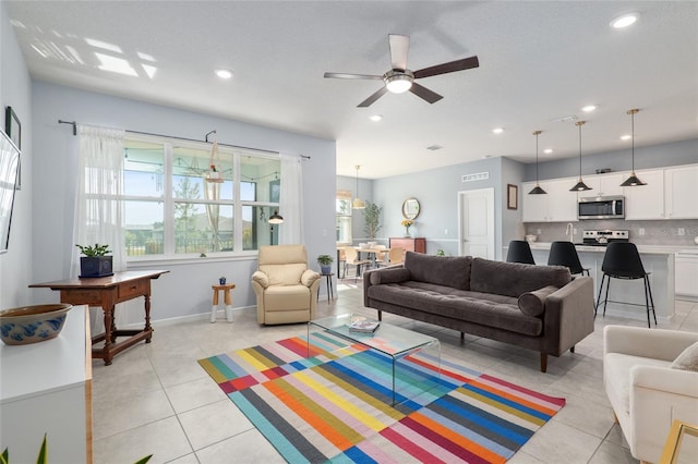 living room with ceiling fan, a wealth of natural light, and light tile patterned floors