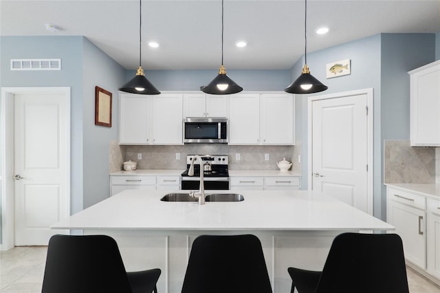 kitchen featuring sink, white cabinetry, hanging light fixtures, appliances with stainless steel finishes, and an island with sink