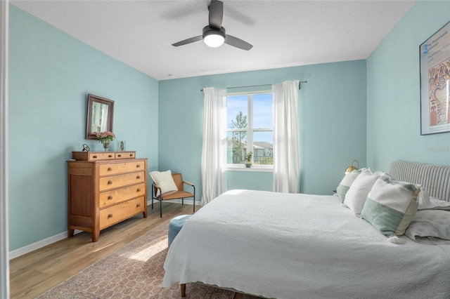 bedroom with ceiling fan, hardwood / wood-style floors, and a textured ceiling