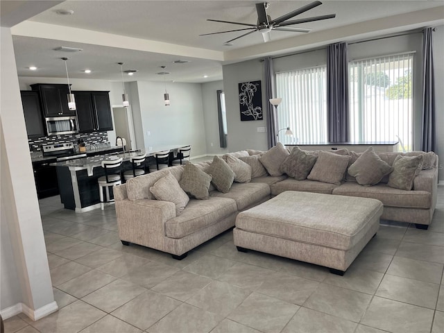 living room featuring ceiling fan, sink, and light tile patterned flooring