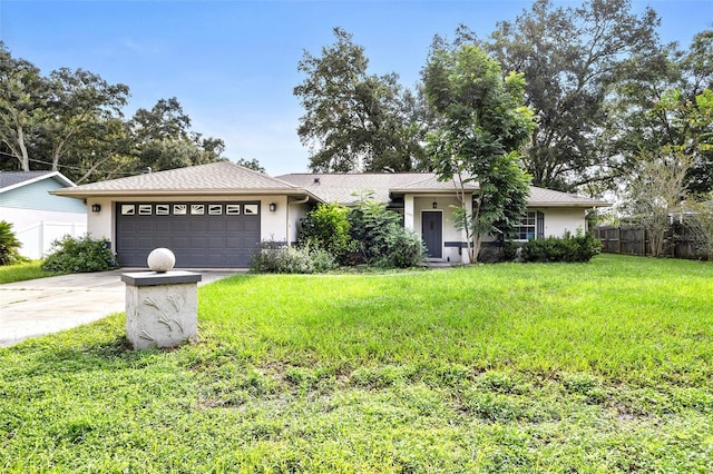 ranch-style home with a garage, fence, concrete driveway, stucco siding, and a front lawn