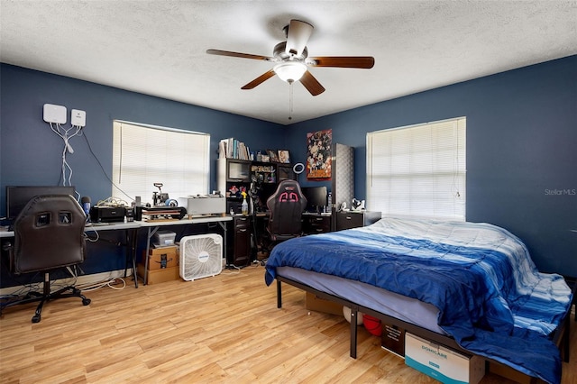 bedroom with ceiling fan, a textured ceiling, and wood finished floors