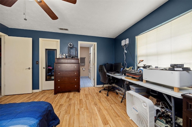 bedroom featuring wood finished floors, visible vents, baseboards, a ceiling fan, and ensuite bath