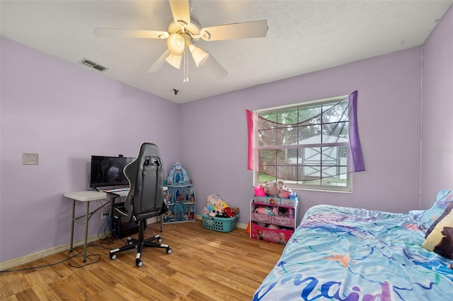 bedroom featuring visible vents, ceiling fan, baseboards, and wood finished floors