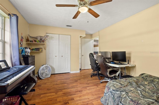 bedroom featuring wood finished floors, visible vents, baseboards, a ceiling fan, and a closet