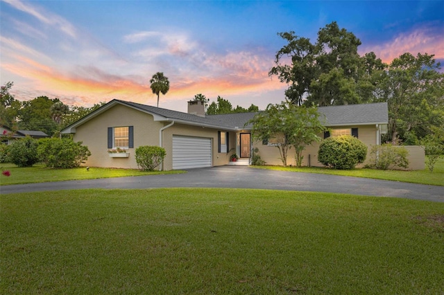 single story home with a garage and a lawn