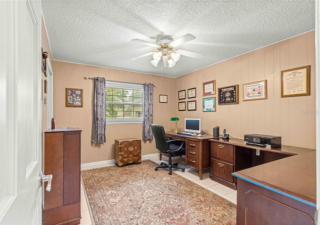 home office featuring a textured ceiling, ceiling fan, wood walls, and light tile patterned flooring