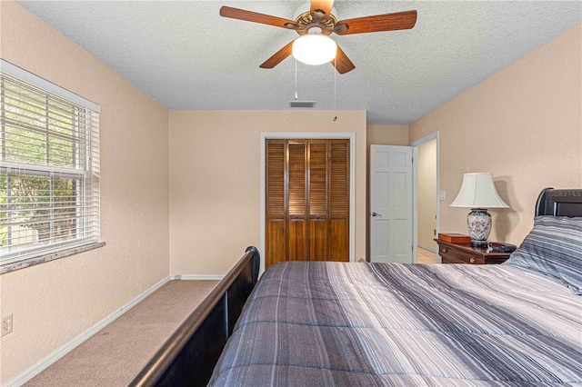 carpeted bedroom with a textured ceiling, ceiling fan, and a closet