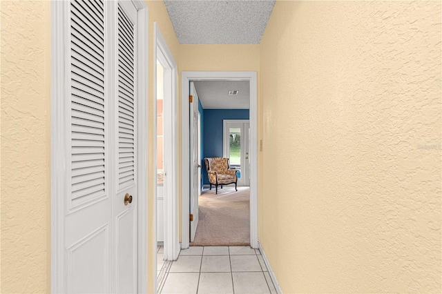 corridor with a textured ceiling and light colored carpet