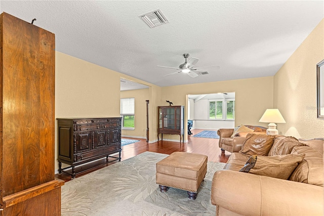 living room with ceiling fan, hardwood / wood-style flooring, and a textured ceiling