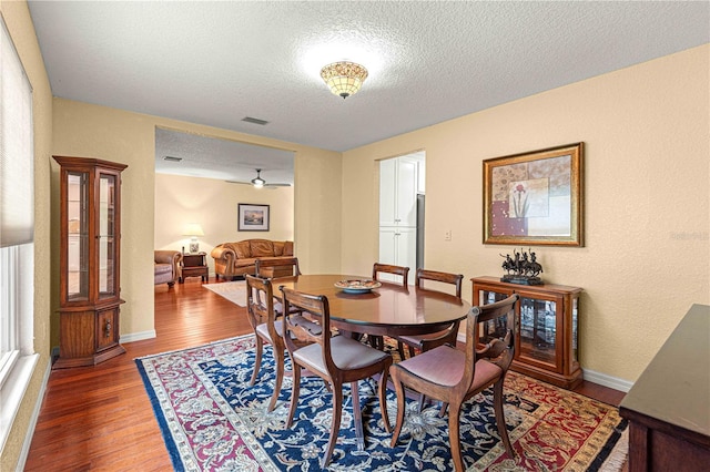 dining room with a textured ceiling, ceiling fan, and dark hardwood / wood-style flooring