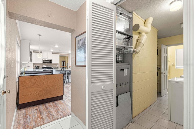 hallway featuring light wood-type flooring, a textured ceiling, and washer / clothes dryer