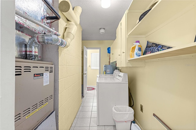 laundry room with cabinets, a textured ceiling, light tile patterned floors, washer and dryer, and heating unit