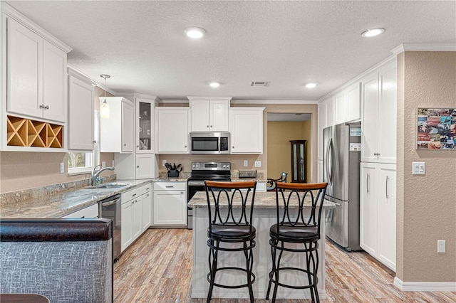 kitchen with light hardwood / wood-style floors, a breakfast bar area, stainless steel appliances, and hanging light fixtures