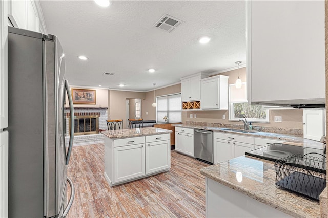 kitchen featuring crown molding, pendant lighting, stainless steel appliances, and a brick fireplace