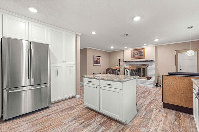 kitchen featuring a fireplace, white cabinetry, light hardwood / wood-style flooring, and stainless steel refrigerator