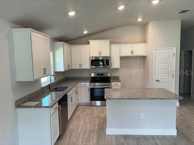 kitchen with appliances with stainless steel finishes, dark stone counters, white cabinets, and a sink