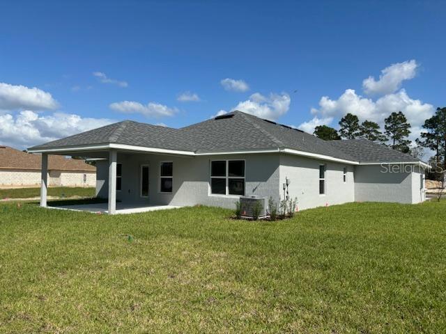 rear view of house with a patio area, stucco siding, a yard, and central air condition unit