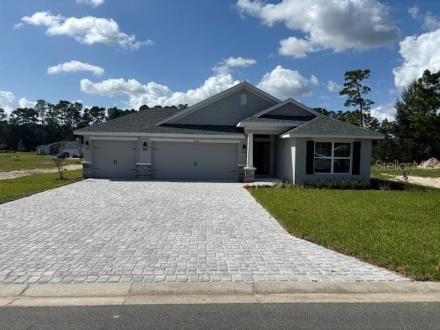 view of front facade featuring a garage, a front lawn, and decorative driveway