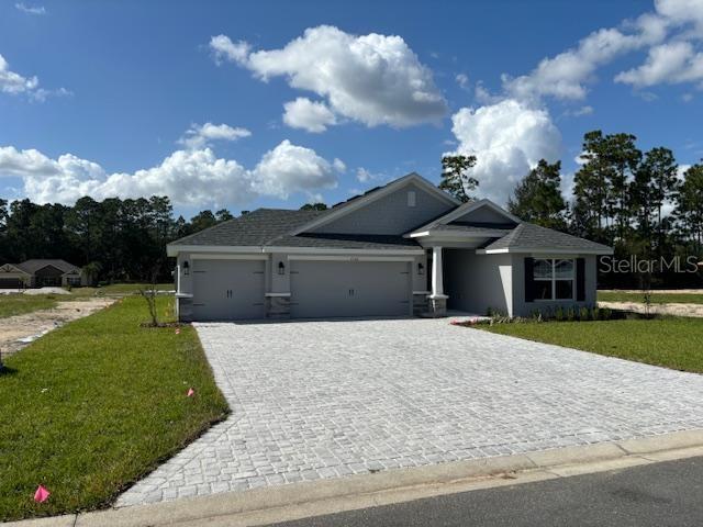 single story home with decorative driveway, a front lawn, and a garage