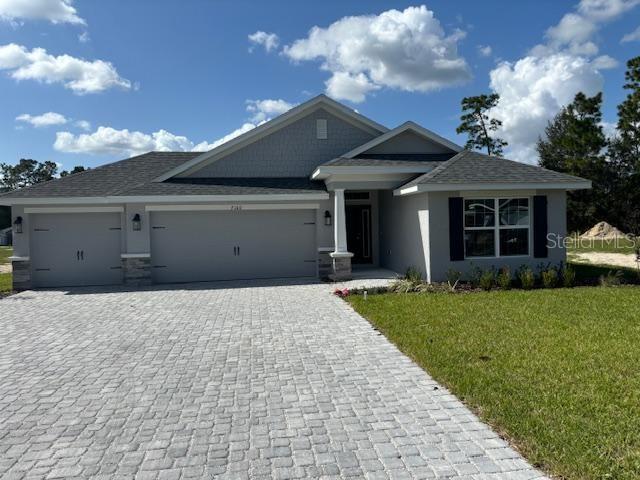 view of front of home featuring a front lawn, decorative driveway, and an attached garage