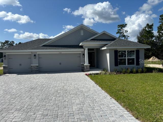 ranch-style house with stucco siding, decorative driveway, a front lawn, and a garage