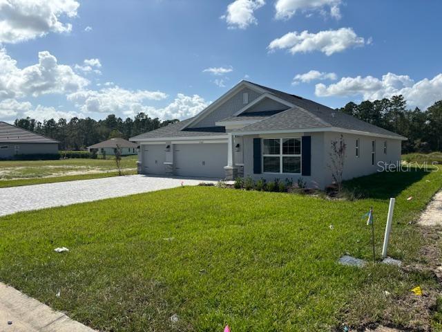 view of front facade with a front lawn, driveway, a garage, and stucco siding