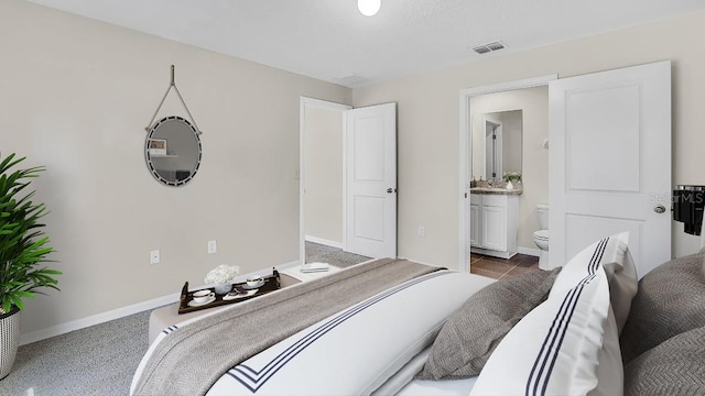 bedroom with connected bathroom and carpet floors