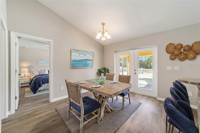 dining space featuring lofted ceiling, french doors, light wood-type flooring, a chandelier, and baseboards