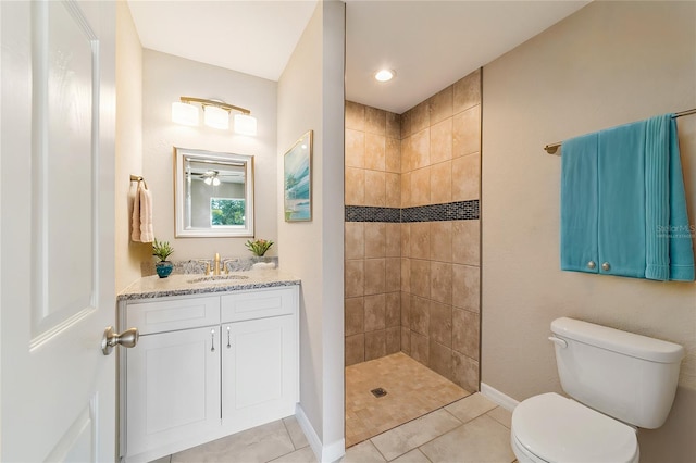 bathroom featuring a tile shower, tile patterned flooring, vanity, and toilet