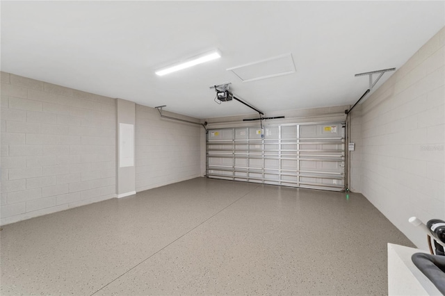garage featuring a garage door opener and concrete block wall