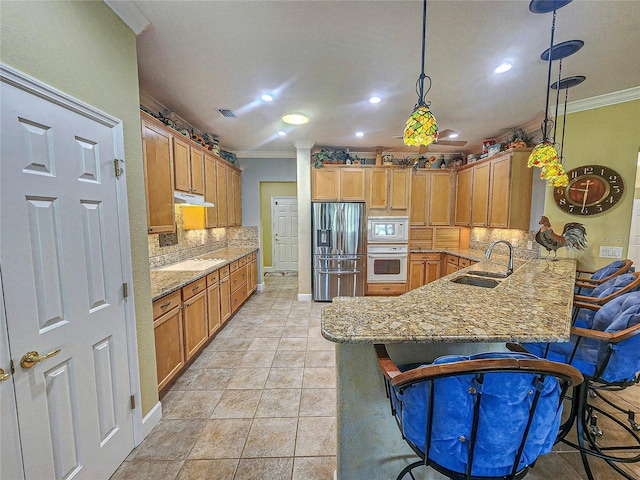 kitchen with crown molding, white appliances, sink, kitchen peninsula, and a breakfast bar area