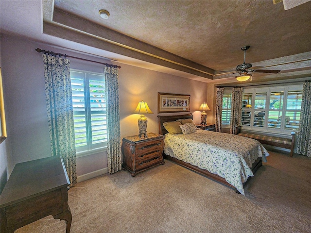 carpeted bedroom featuring a tray ceiling, a textured ceiling, and ceiling fan