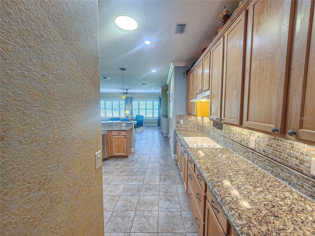 kitchen featuring crown molding, decorative light fixtures, light stone countertops, light tile patterned flooring, and tasteful backsplash