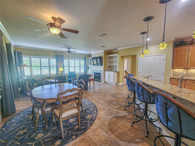 dining area with a textured ceiling, ceiling fan, ornamental molding, and tile patterned floors