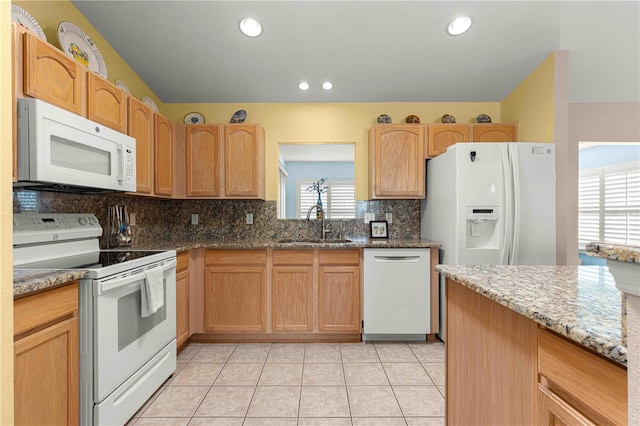 kitchen featuring light stone countertops, white appliances, sink, and a wealth of natural light