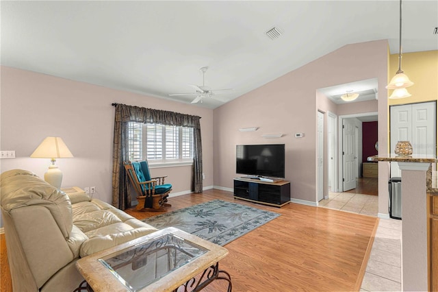 living room with ceiling fan, lofted ceiling, and light wood-type flooring