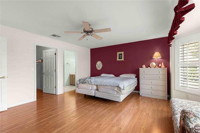 bedroom featuring ceiling fan, light wood-type flooring, and connected bathroom