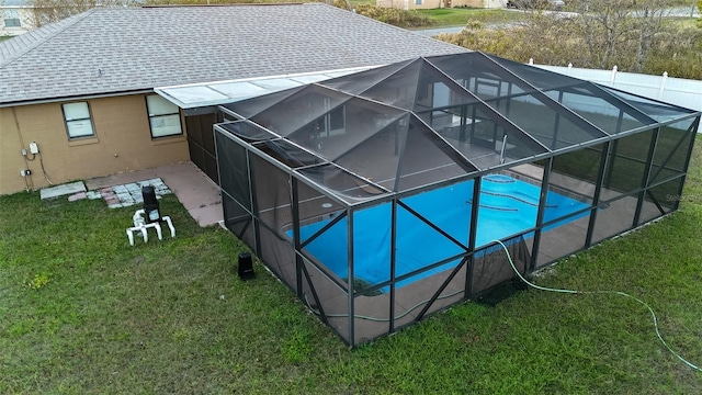 view of swimming pool featuring a lawn, a patio area, and a lanai