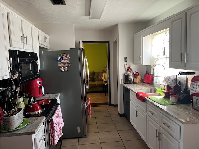 kitchen with white cabinets, light tile patterned floors, sink, and black appliances