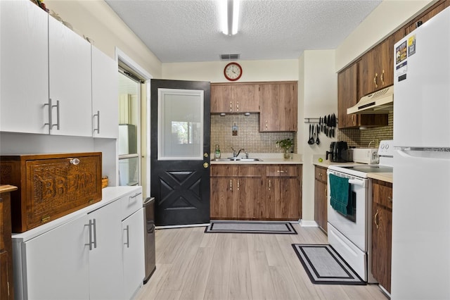 kitchen featuring a textured ceiling, white appliances, light hardwood / wood-style flooring, sink, and white cabinets