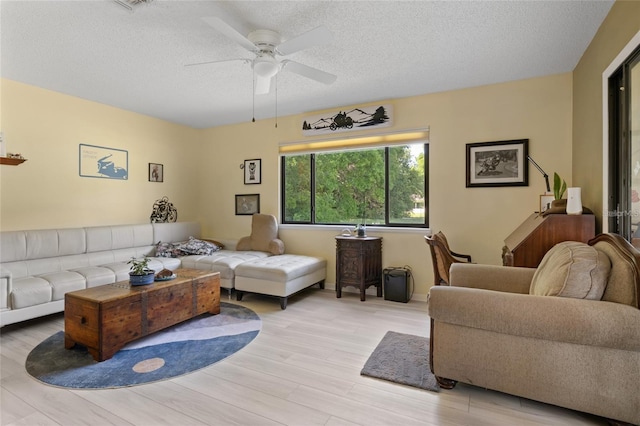 living room featuring a textured ceiling, ceiling fan, and light hardwood / wood-style floors