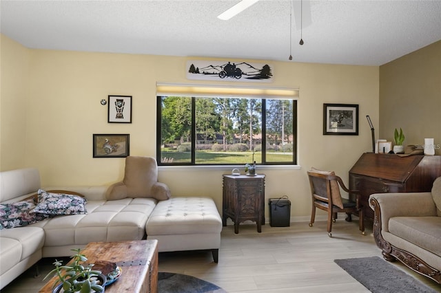 living room featuring a textured ceiling, ceiling fan, and light wood-type flooring