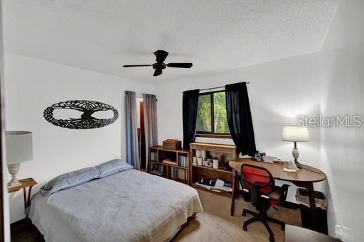 carpeted bedroom with a textured ceiling and ceiling fan