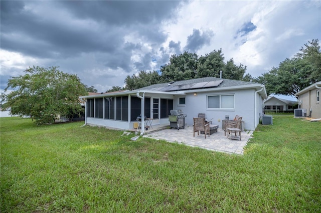 rear view of house with a lawn, a patio area, solar panels, and a sunroom