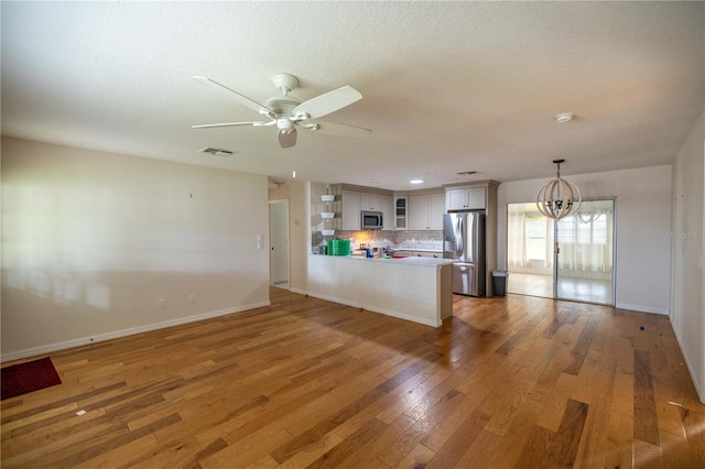 unfurnished living room featuring hardwood / wood-style floors, ceiling fan with notable chandelier, and a textured ceiling