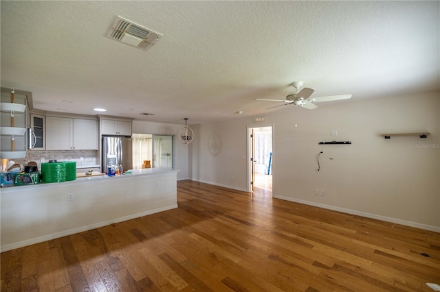 unfurnished living room with a textured ceiling, ceiling fan, and hardwood / wood-style floors