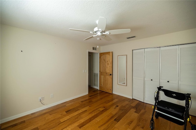 bedroom with a textured ceiling, hardwood / wood-style floors, ceiling fan, and a closet