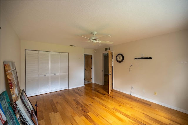 unfurnished bedroom featuring light wood-type flooring, a textured ceiling, ceiling fan, and a closet