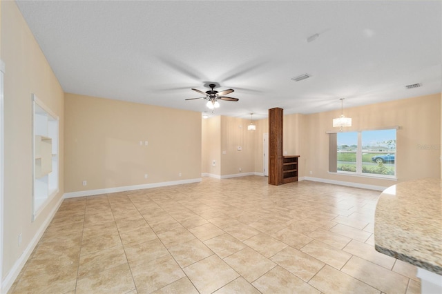 unfurnished living room featuring ceiling fan with notable chandelier